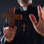 Jihadist Abduction Adds Chilling Twist Clergyman holding wooden cross with hand raised
