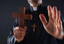 Jihadist Abduction Adds Chilling Twist Clergyman holding wooden cross with hand raised