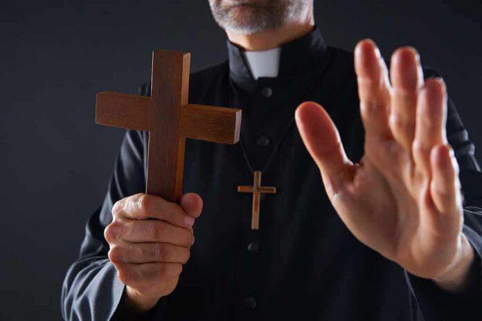Clergyman holding wooden cross with hand raised