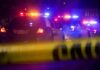 Police cars with flashing lights behind yellow caution tape at night