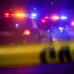 A Property Dispute Ended in First-Degree Murder Police cars with flashing lights behind yellow caution tape at night