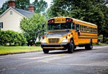 Yellow school bus driving on a suburban street