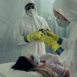 Healthcare workers in protective gear attending to a patient