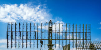 Military radar system displayed at an outdoor exhibition under a blue sky