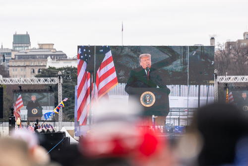 President,Trump,Was,Making,A,Speech,At,The,Eclipse,On A large screen displays a speaker at a political rally with American flags in the foreground