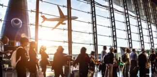 Passengers queue inside an airport terminal at sunset