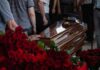 Casket surrounded by red roses at a funeral