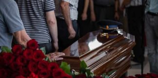 Casket surrounded by red roses at a funeral