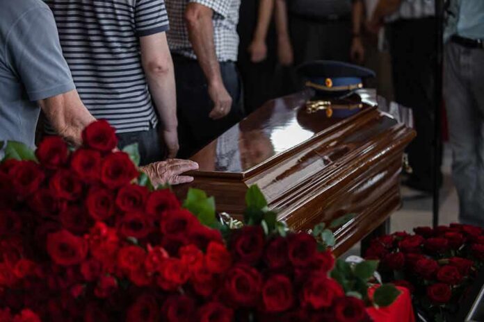 Casket surrounded by red roses at a funeral