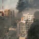 The Safe Zone Paradox in Gaza A cityscape showing damaged buildings and thick smoke rising from the ground