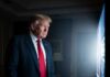 Trump’s Russia Plan Meets China’s Resistance A man in a suit and red tie watching a television screen in a dimly lit room