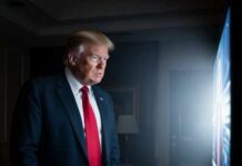 Trump’s Russia Plan Meets China’s Resistance A man in a suit and red tie watching a television screen in a dimly lit room