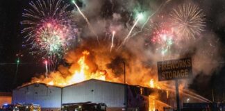 A large building engulfed in flames with fireworks in the sky