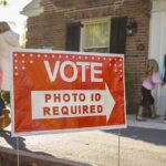 The Voter ID Battle Just Shifted Red voting sign with arrow near people entering a polling place