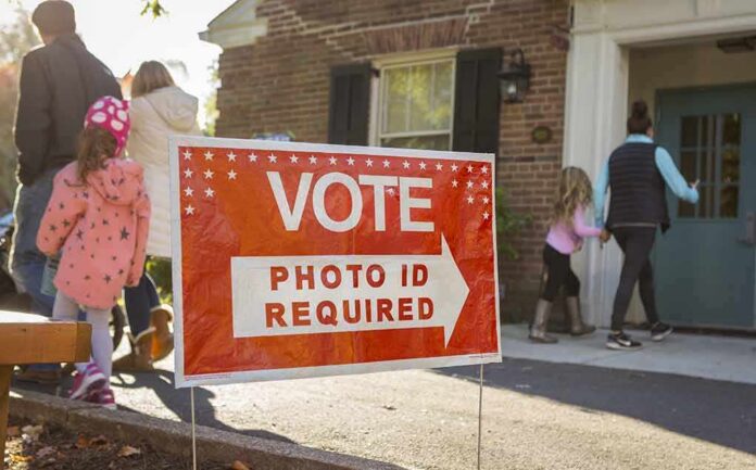 shutterstock_512254585 Red voting sign with arrow near people entering a polling place