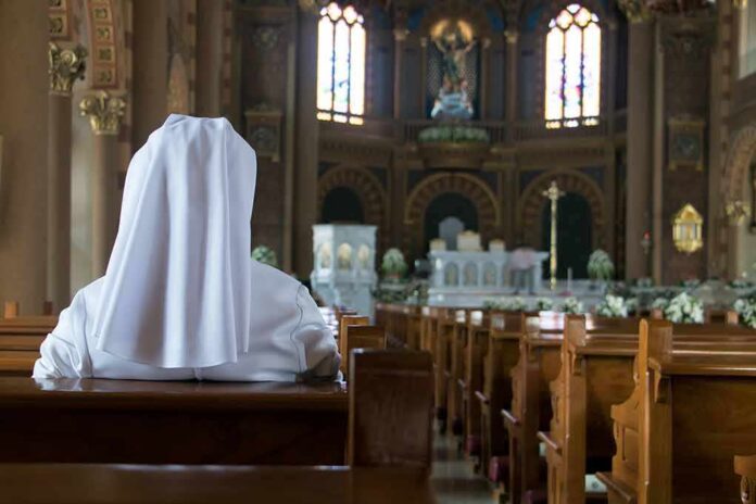 Person in white habit seated in a church pew facing the altar