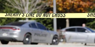 Sheriff's line tape blocking a street with police cars behind