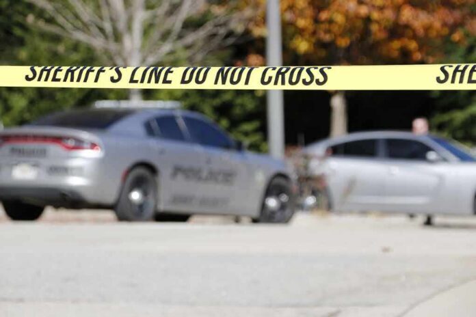 shutterstock_1251185893 Sheriff's line tape blocking a street with police cars behind