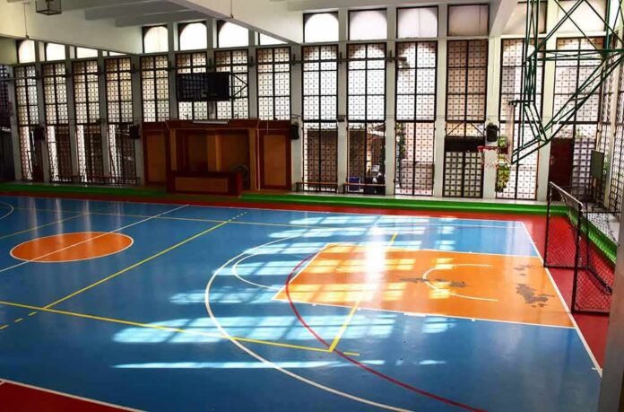 shutterstock_1350851069 Indoor basketball court with blue floor and orange key areas