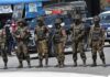 Coordinated Blasts Rock Thailand’s South Soldiers in camouflage gear stand in a line on a city street