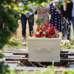 White coffin with red flowers at outdoor burial