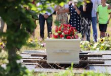 Student Medic Killed Mid-Rescue White coffin with red flowers at outdoor burial