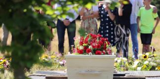 White coffin with red flowers at outdoor burial