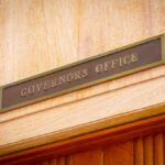 Blue-State Crackdown Meets Defiant Sheriff Governor's Office sign above a wooden doorway