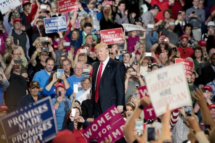 shutterstock_605507825 man in suit on stage at crowded rally