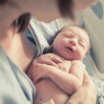 newborn baby sleeping in a parent's arms