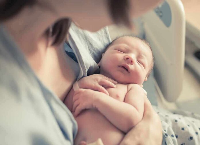 shutterstock_663728050 newborn baby sleeping in a parent's arms