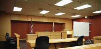 Interior view of an empty courtroom with wooden furniture and American flags