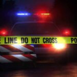 Police car behind crime scene tape at night