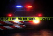 Police car behind crime scene tape at night