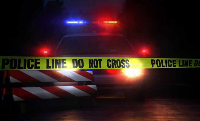 shutterstock_693454099-1 Police car behind crime scene tape at night