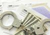 Handcuffs on tax forms with cash