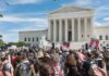 Crowd of protesters outside a neoclassical courthouse