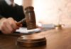 Judge's gavel striking sound block on wooden desk