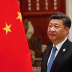 Loyalty Over Firepower — Xi’s Hard Pivot Xi Jinping standing beside a Chinese flag