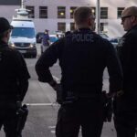 Spy Shrub Ambushes Drivers Police officers stand on a city street