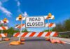 Road closed barricade with orange sandbags on a sunny day