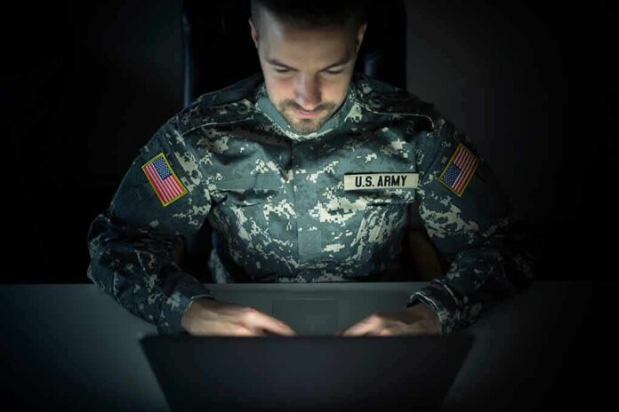 shutterstock_1420136774 Soldier in camouflage uniform using a laptop in a dark room