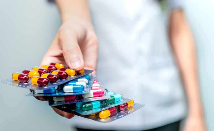 Hand holding blister packs of assorted capsules