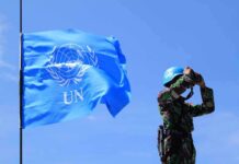 Security Lockdown As Fiery Speeches Loom UN peacekeeper with blue helmet looks through binoculars beside UN flag