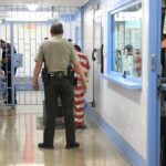 Understaffed Jail, Unthinkable Outcome Corrections officers escort an inmate in a jail hallway
