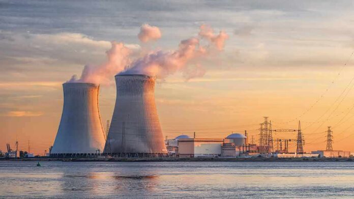 Nuclear power plant with cooling towers emitting steam at sunset