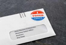 Low-Turnout Shock Tips A Safe Seat Absentee ballot envelope with I Voted sticker on dark surface
