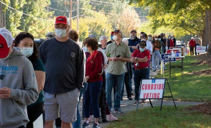shutterstock_1834288405 Christian Jones and others waiting in a long line outside a polling place