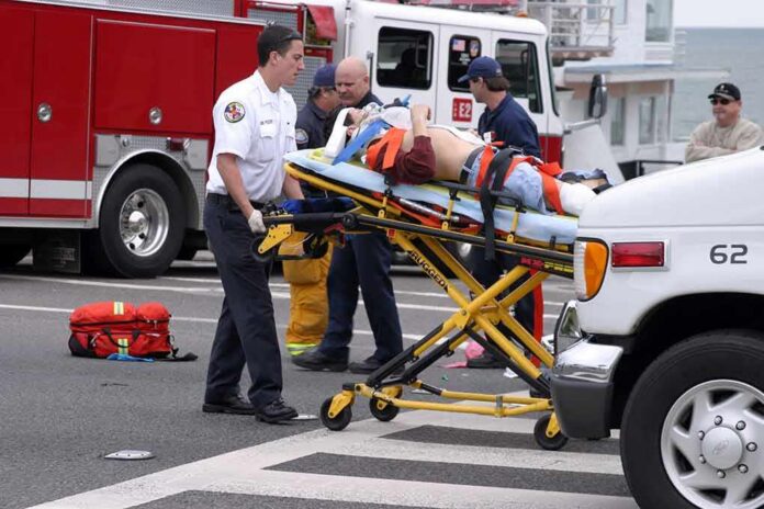 Paramedics wheel an injured person on a stretcher toward an ambulance