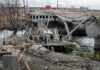 People crossing a destroyed concrete bridge over a river